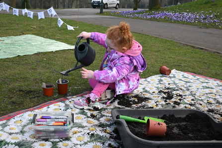 Child in purple coat playing with watering can