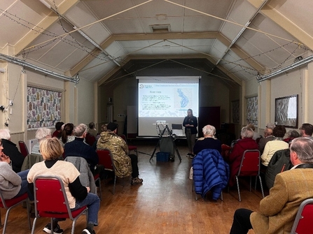 A small, angular hall with a presentation projected at the far end.