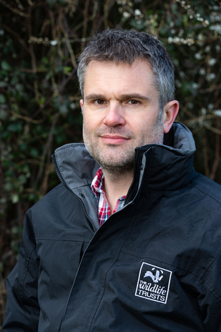 Craig Bennett standing in front of a hedge