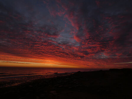 A very deep red with tones of orange sunrise across the sea