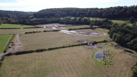 An aerial shot of some fields, with patches of water showing the floodplain area