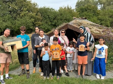 group of people stood together holding a hedgehog house andd bird boxes