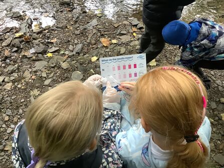 Two young volunteers colour match their water sample to the water qualitychart