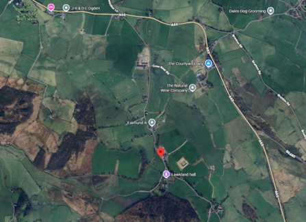 Aerial map of rural green landscape with roads and labeled locations, including "The Dalesbridge Campsite and Cabins," "JR & D L Ogden," "The Courtyard Dairy," "The Natural Wine Company," and "Lawkland Hall," with a red location marker indicating a specific point.