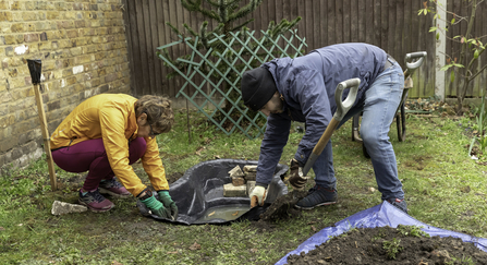 Two people creating a pond