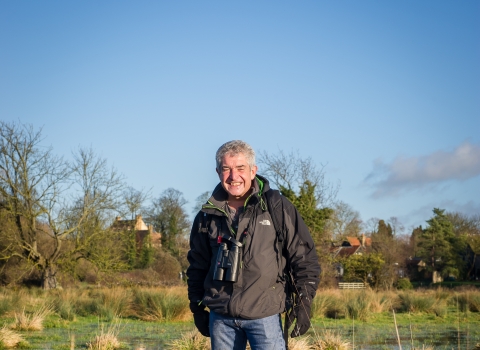 Tony stands in a wetland with his dogs