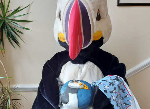 Our puffin mascot, Cliff holding a beautifully decorated puffin cake.