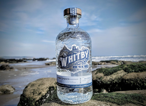 Bottle of Whitby Gin on rock with sea in background