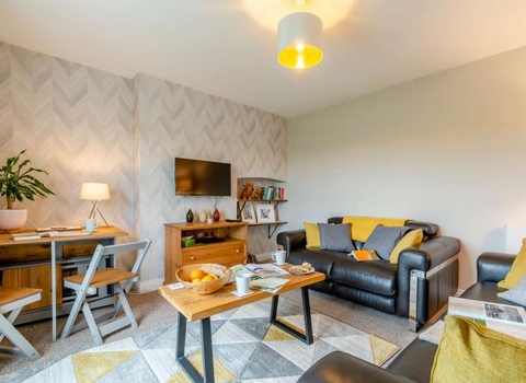 Living room decorated in grey and mustard colours, with two sofas, a coffee table and a desk