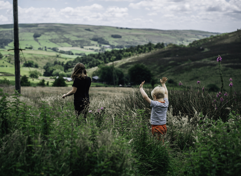 Two children running through a meadow