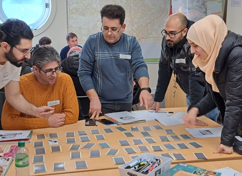 community group of people stood round a table looking at cards on the table and creating an idea board