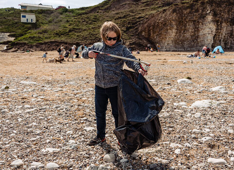 A young boy picking litter on Flamborough beach.