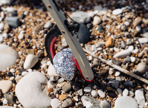 Image showing a litter picker up close picking up a ball of foil from a pebble beach