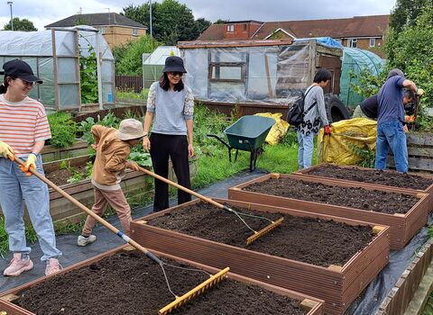 Adults and children build raised beds in a community garden. 