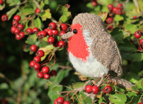 A Knitted Robin that is sitting in a berry tree 